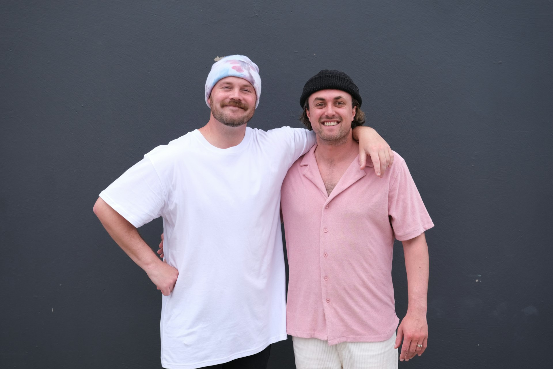 Two men wearing beanies standing beside each other