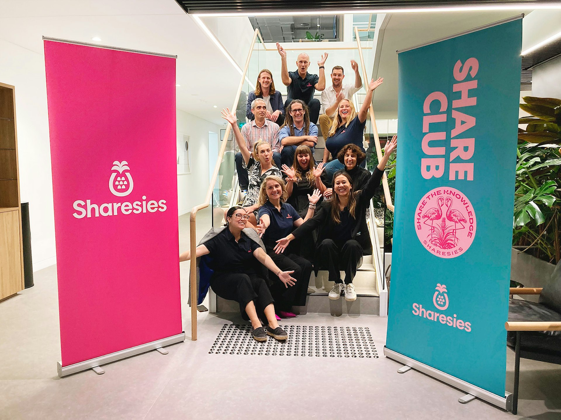 A group of people from the Sharesies team sitting on the stairs smiling