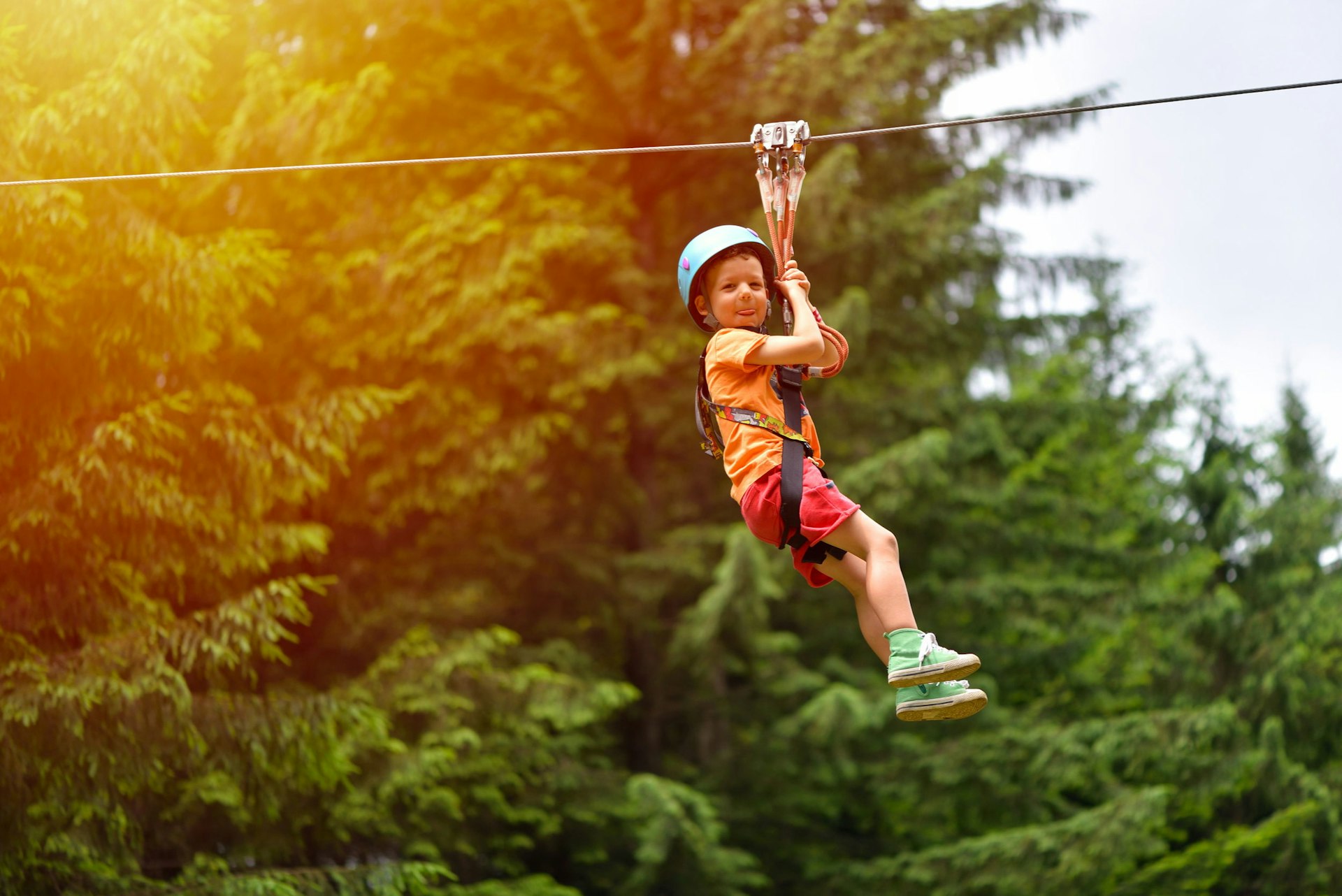 A boy on a zip-line pokes his tongue out.