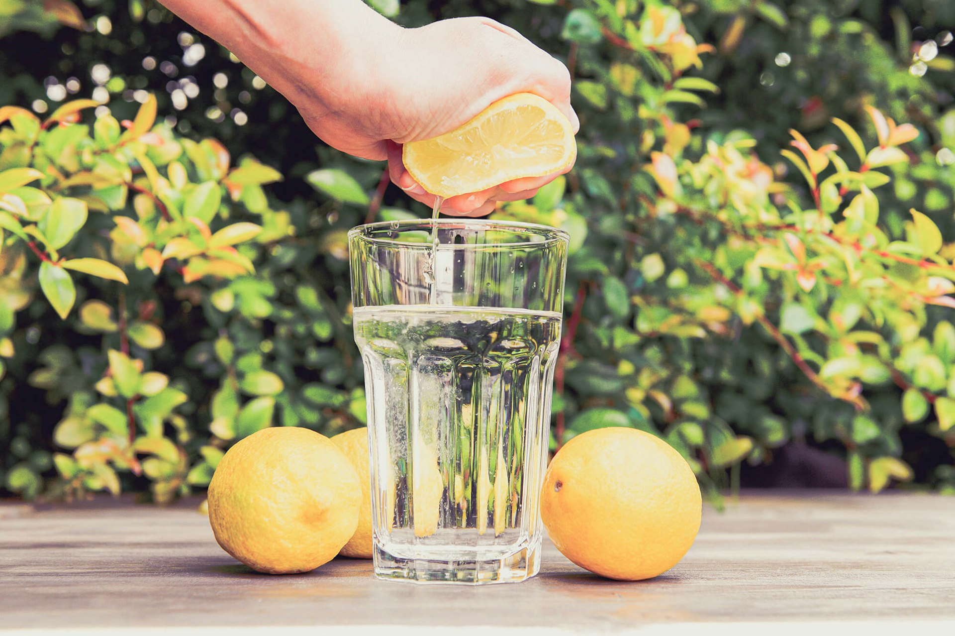 A hand squeezing half a lemon into a glass.