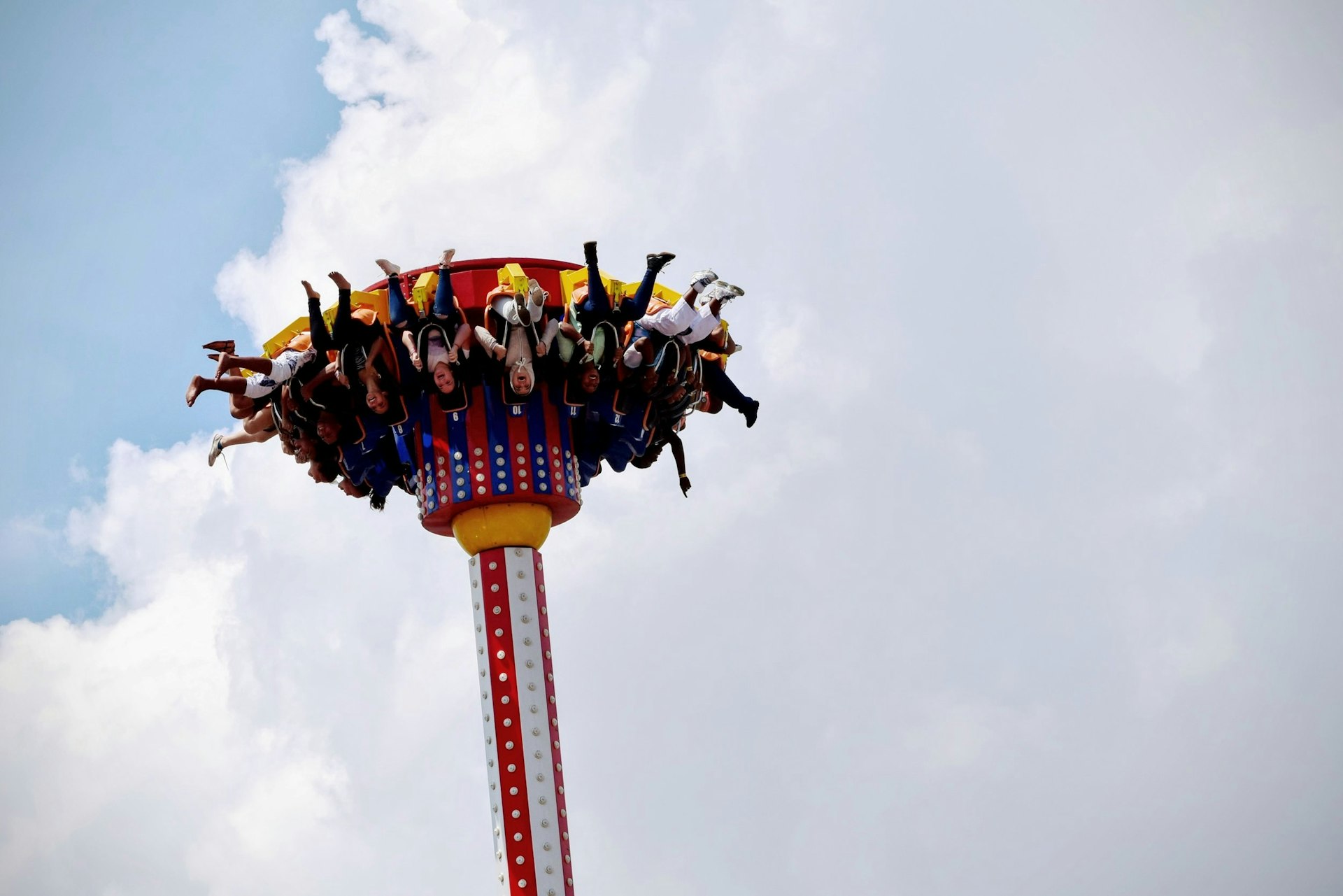 Photo of an amusement park ride holding people upside down, while strapped in their chairs.