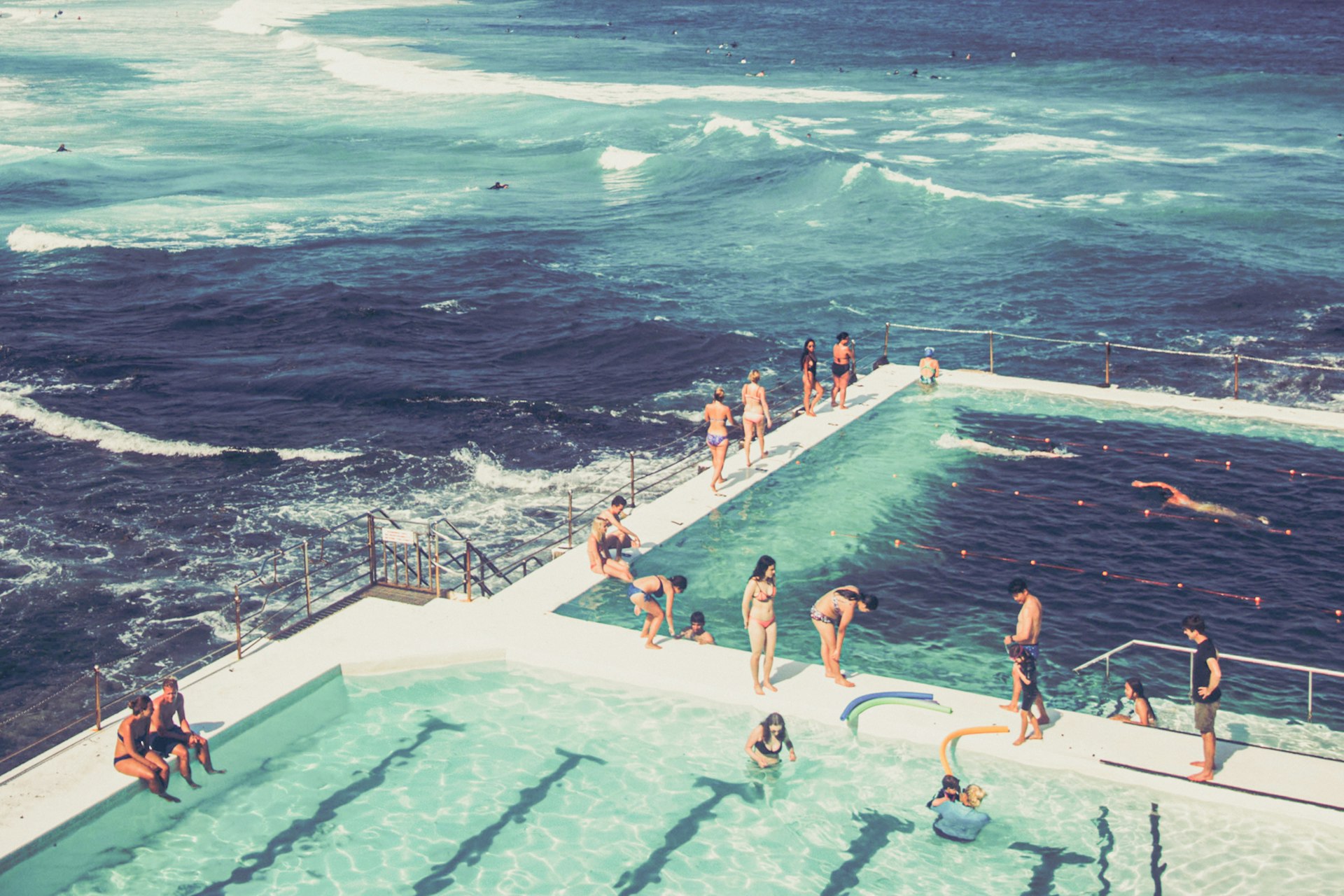 Several people are enjoying their time in a popular beachside ocean pool.
