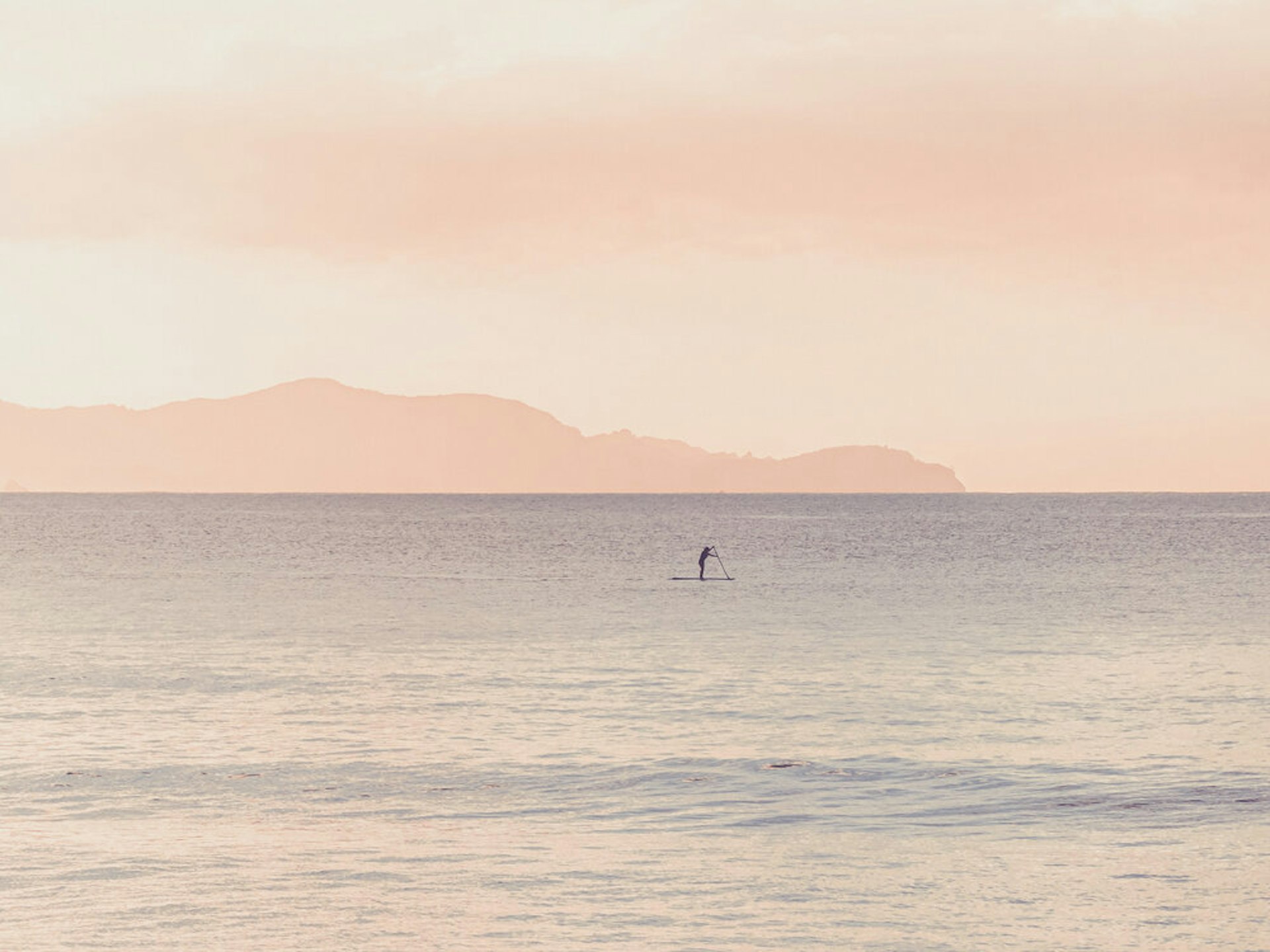 Ocean with lone stand-up paddle boarder in the distance.