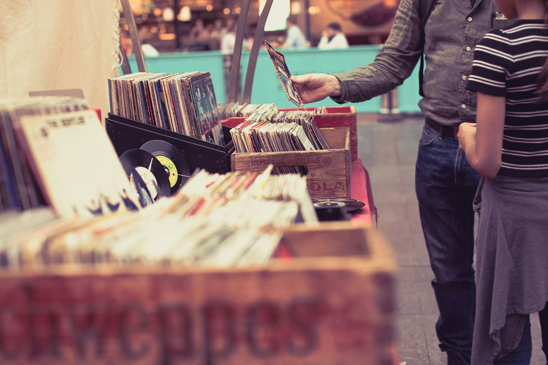 A man picks up a vinyl record from a box on a table.
