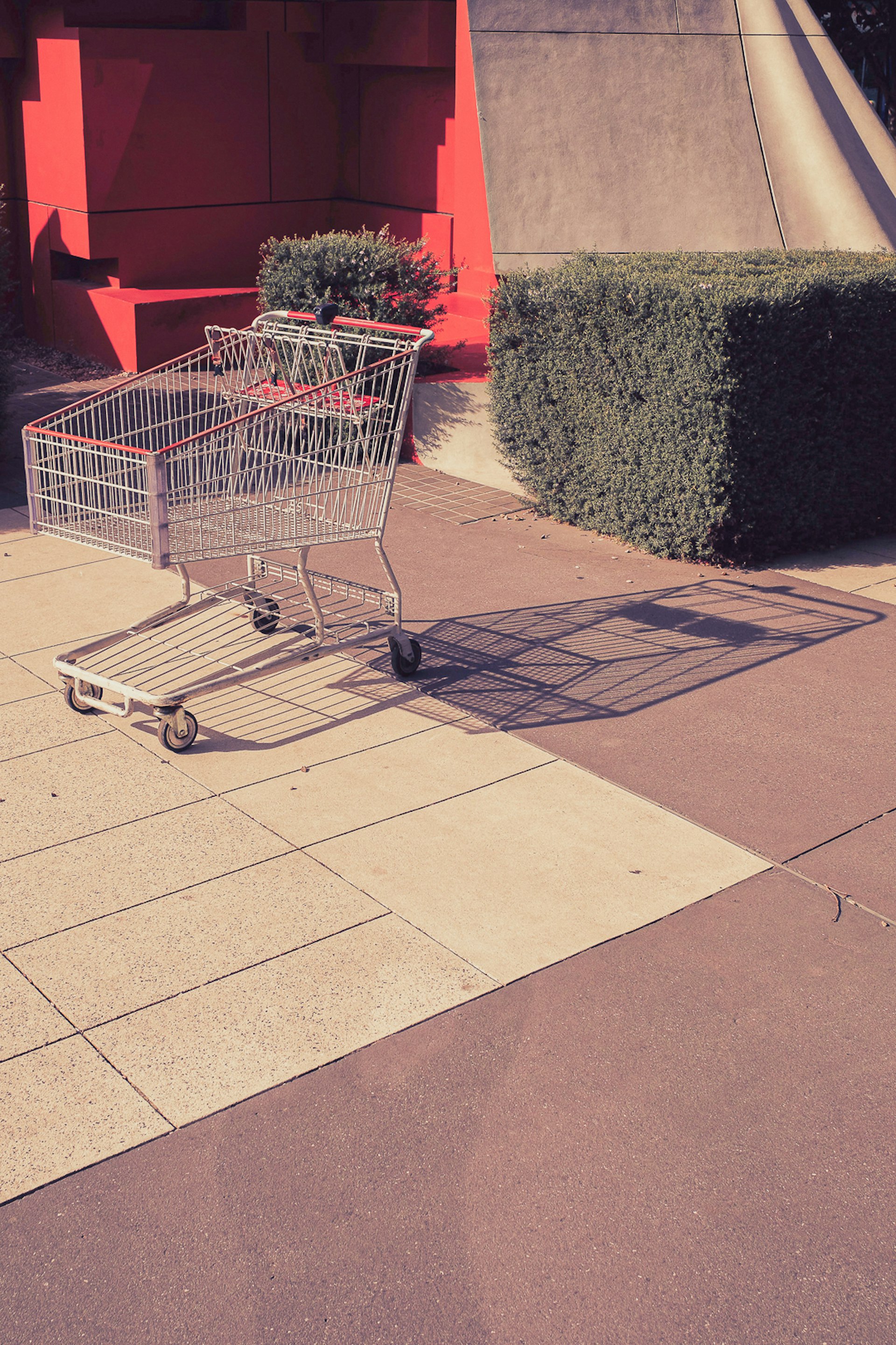 An empty shopping trolley stands in a courtyard.