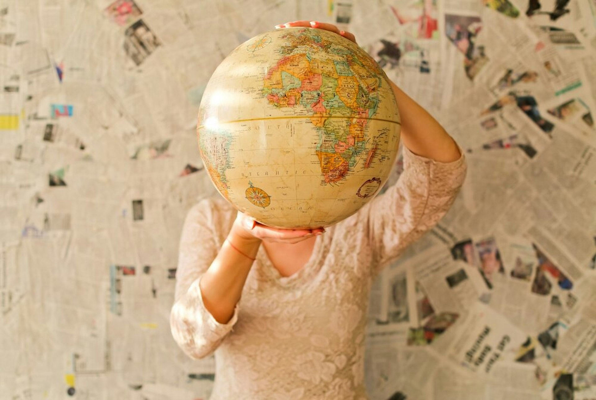 A person holding a world globe in front of their face.